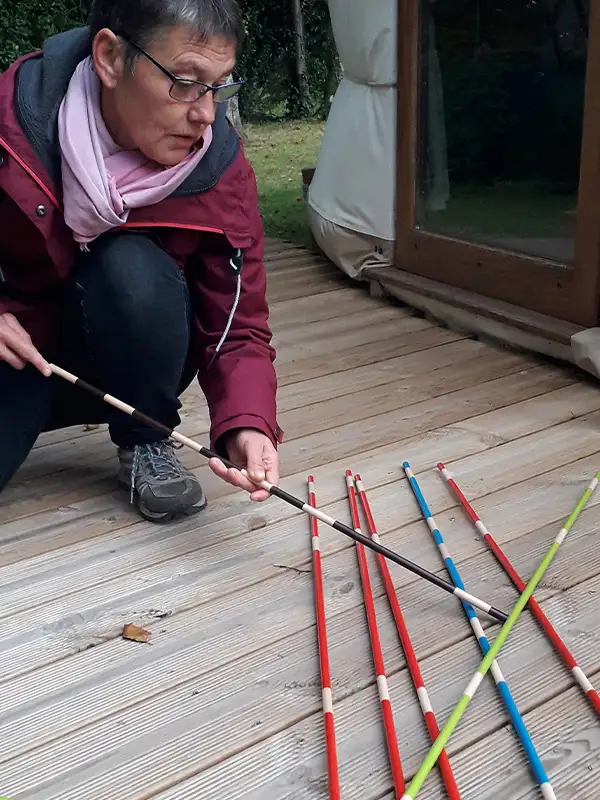 Mikado XXL - Disponible Au Grand Air (01) une femme joue au Mikado géant d'Au Grand Air